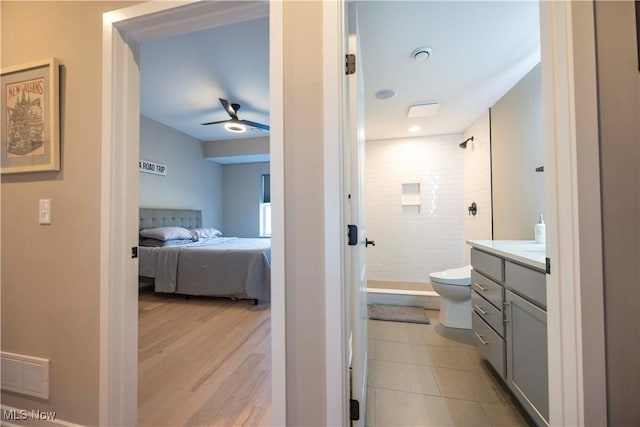 full bath with vanity, a ceiling fan, visible vents, tiled shower, and toilet