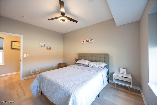 bedroom featuring visible vents, baseboards, light wood-style flooring, and a ceiling fan