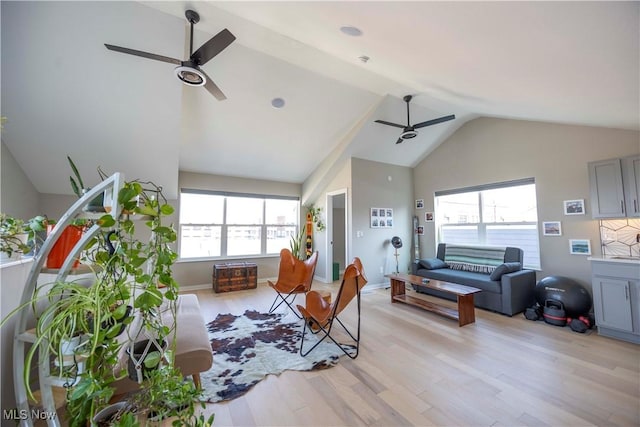 living room with baseboards, light wood finished floors, a ceiling fan, and vaulted ceiling