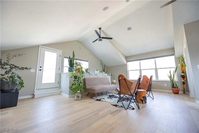 living area with light wood finished floors, baseboards, ceiling fan, and vaulted ceiling