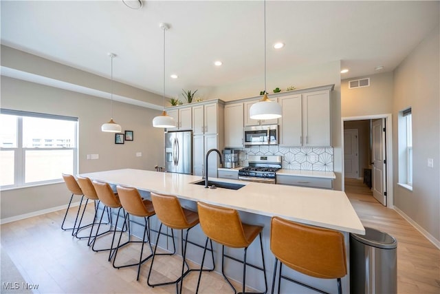 kitchen featuring a sink, stainless steel appliances, a large island, a kitchen breakfast bar, and backsplash