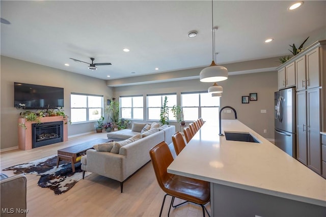 living room with recessed lighting, light wood-type flooring, baseboards, and a fireplace