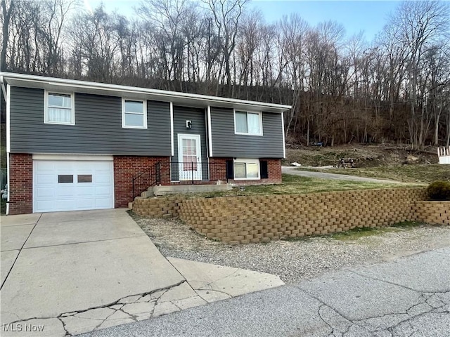 split foyer home featuring brick siding, driveway, and an attached garage