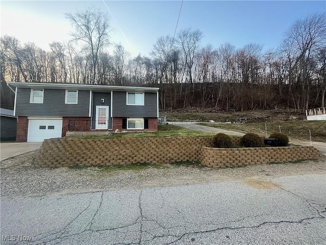 split foyer home with a garage, brick siding, and concrete driveway