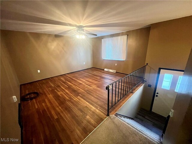 stairs with ceiling fan, visible vents, and wood finished floors