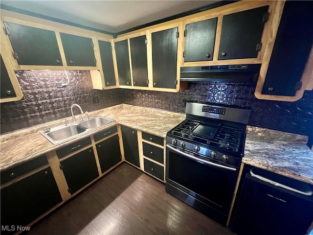 kitchen featuring a sink, under cabinet range hood, decorative backsplash, stainless steel gas range, and dark wood-style flooring