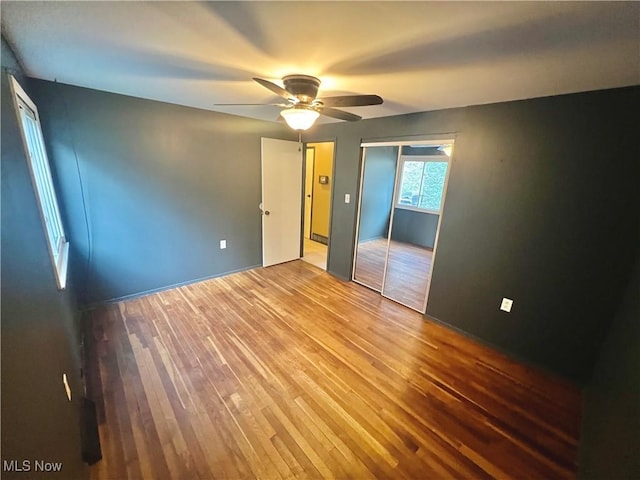 unfurnished bedroom with a ceiling fan, wood finished floors, and a closet