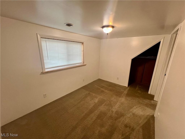 unfurnished room with visible vents and dark colored carpet