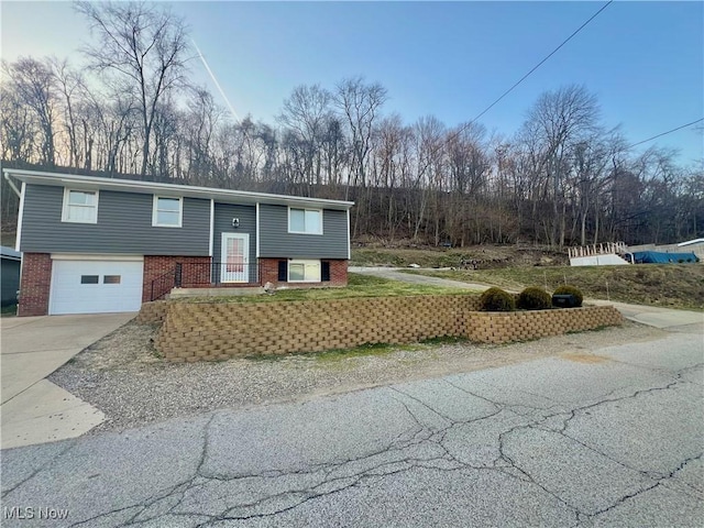 bi-level home featuring brick siding, a garage, and driveway