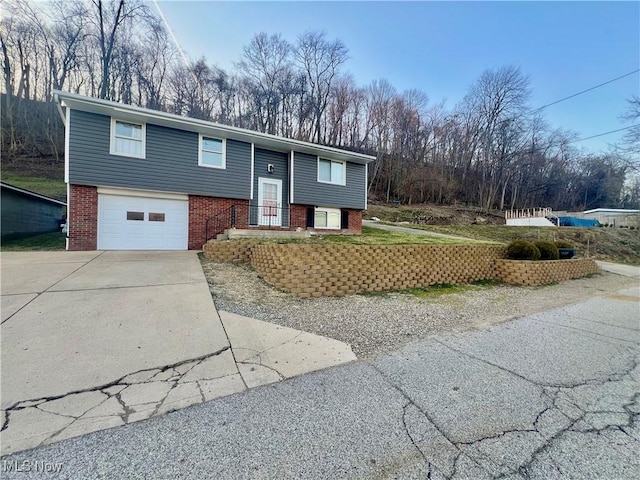 raised ranch with brick siding, driveway, and a garage