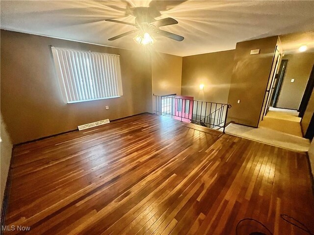 unfurnished room featuring hardwood / wood-style flooring, a ceiling fan, and visible vents