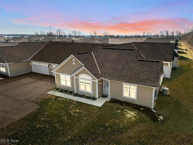 view of front of home featuring aphalt driveway, a residential view, cooling unit, and a garage