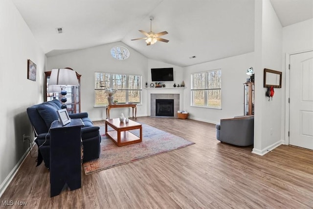 living area featuring a fireplace, vaulted ceiling, wood finished floors, and visible vents