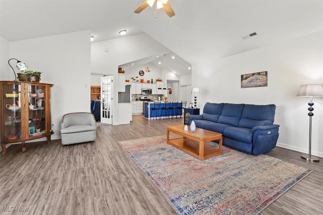 living area featuring baseboards, visible vents, high vaulted ceiling, ceiling fan, and light wood-style floors