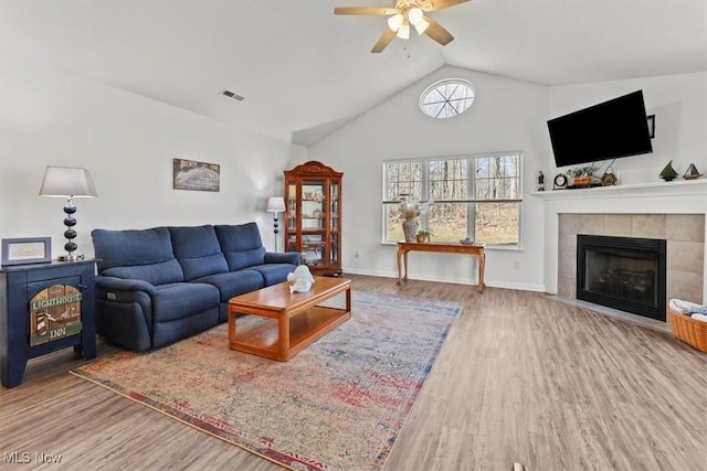 living area with visible vents, wood finished floors, a fireplace, baseboards, and vaulted ceiling