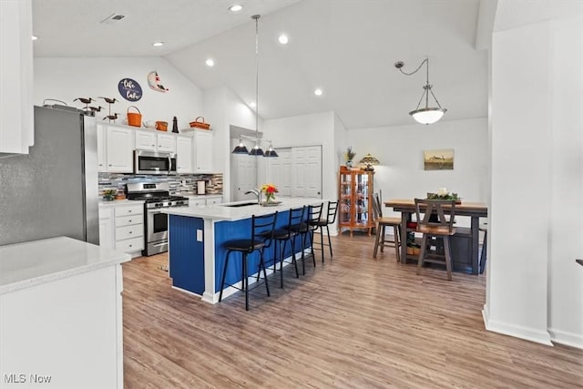 kitchen featuring appliances with stainless steel finishes, a breakfast bar area, light countertops, and white cabinetry