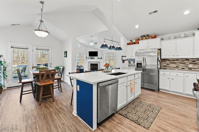 kitchen featuring visible vents, a fireplace, a sink, stainless steel appliances, and light countertops