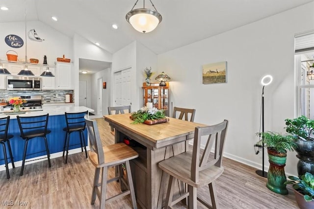 dining area with recessed lighting, baseboards, light wood-style flooring, and vaulted ceiling