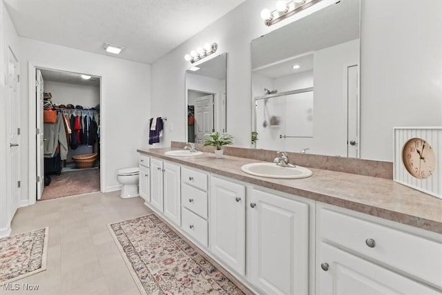 full bath featuring double vanity, a spacious closet, a stall shower, and a sink