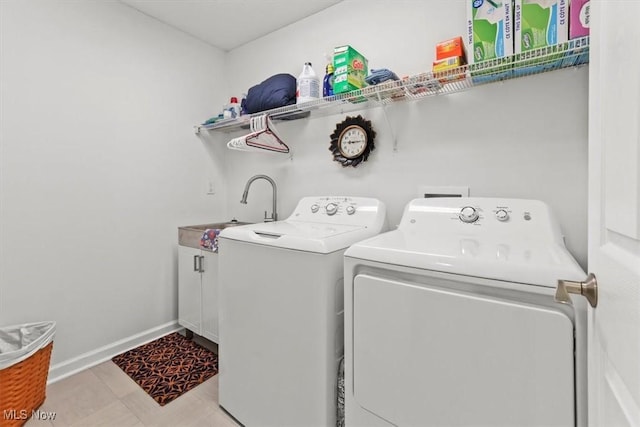 clothes washing area with washer and clothes dryer, cabinet space, baseboards, and a sink