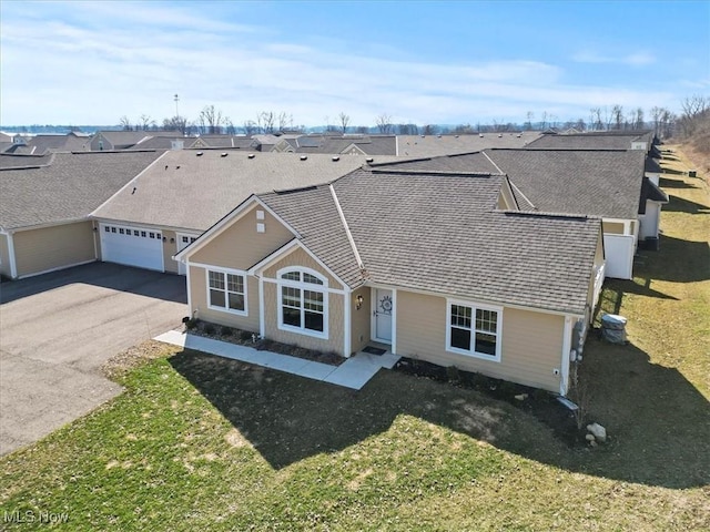 view of front facade with a front yard, cooling unit, a garage, aphalt driveway, and a residential view