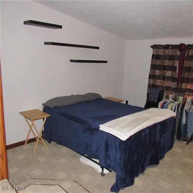 bedroom featuring baseboards, carpet floors, a textured ceiling, and vaulted ceiling