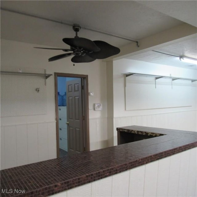 kitchen featuring dark countertops, a wainscoted wall, and white cabinets