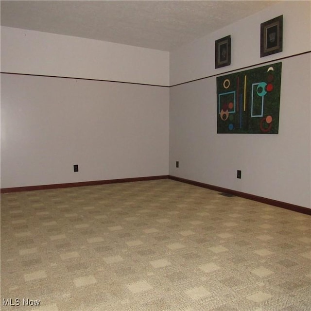 spare room featuring light colored carpet and baseboards