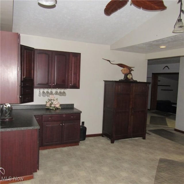 kitchen featuring dark countertops, a textured ceiling, lofted ceiling, and reddish brown cabinets