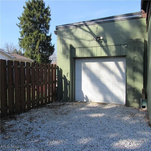 garage featuring gravel driveway and fence