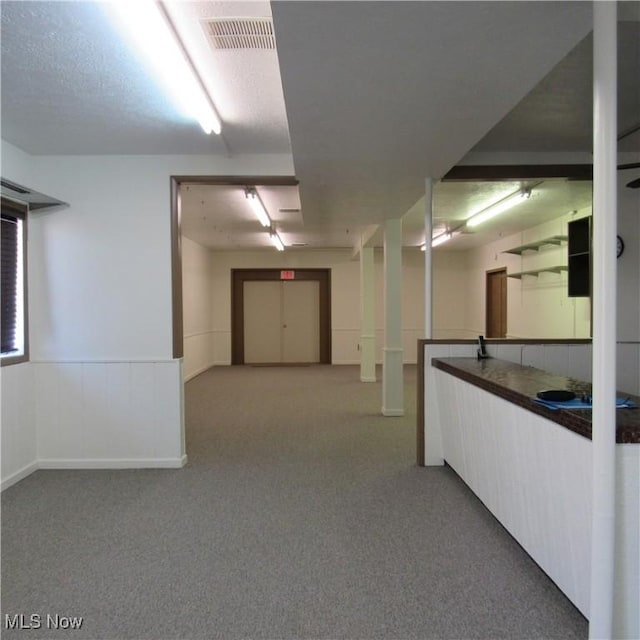 hall featuring a wainscoted wall, visible vents, and carpet floors