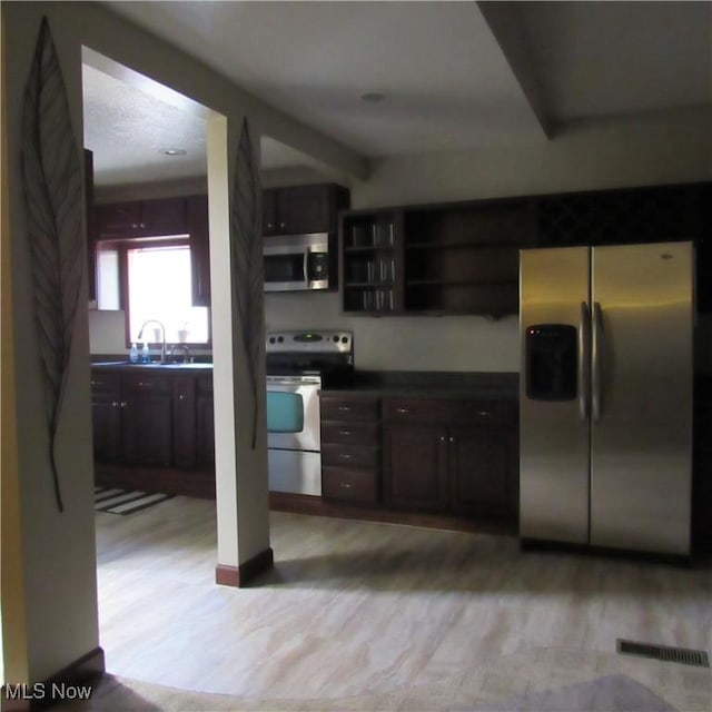 kitchen with dark countertops, light wood-style flooring, visible vents, and appliances with stainless steel finishes