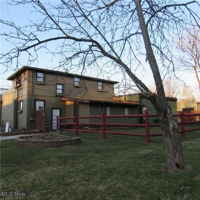 rear view of house with a lawn and fence