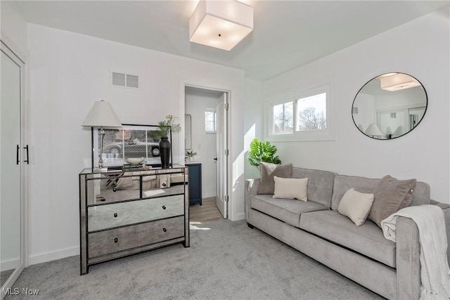 living area with light carpet, visible vents, and baseboards