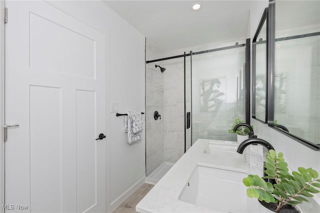 bathroom with double vanity, a stall shower, and a sink