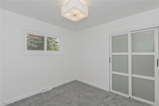 unfurnished room with visible vents, carpet, and baseboards