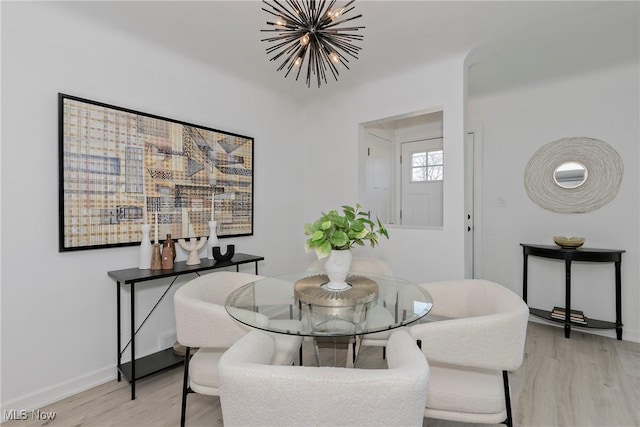 dining area featuring light wood-style flooring, baseboards, and a chandelier