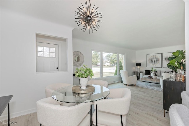 dining area with a notable chandelier, a healthy amount of sunlight, light wood-style flooring, and baseboards