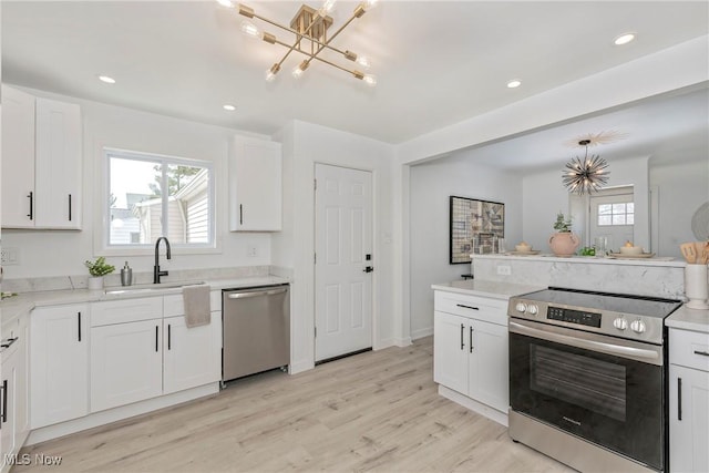 kitchen with white cabinets, light wood finished floors, appliances with stainless steel finishes, and a sink