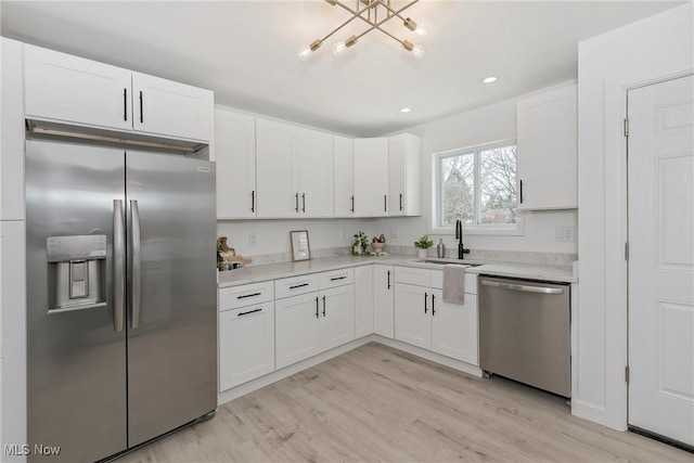 kitchen with a sink, light wood-type flooring, white cabinetry, and stainless steel appliances