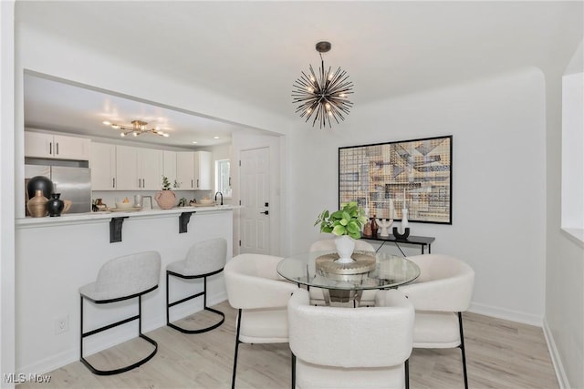 dining space featuring a chandelier, light wood-style flooring, and baseboards