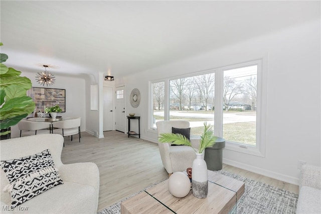 living area with baseboards, plenty of natural light, and light wood-style floors