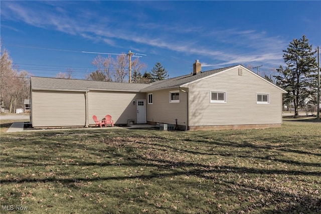 rear view of property with a chimney and a yard