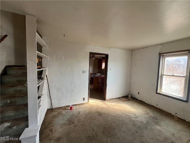 carpeted empty room featuring stairway