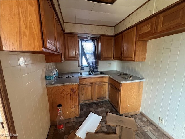 kitchen featuring brown cabinets, tile walls, and a sink