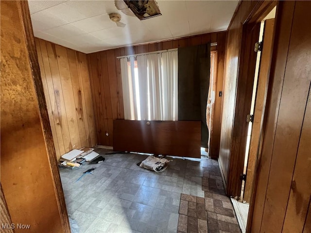 unfurnished room with tile patterned floors and wooden walls