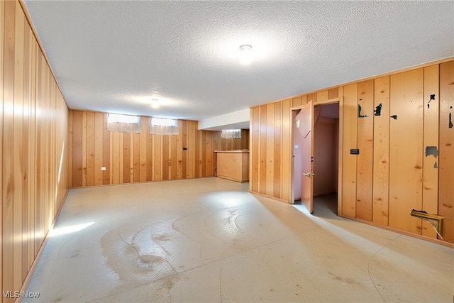 below grade area featuring wooden walls and a textured ceiling