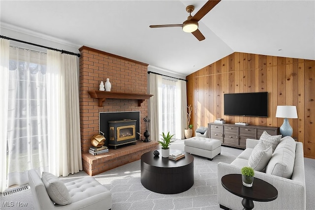 living area featuring a wealth of natural light, wood walls, a ceiling fan, and vaulted ceiling