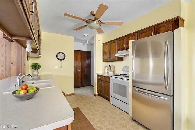 kitchen with white range with electric cooktop, under cabinet range hood, a sink, freestanding refrigerator, and light countertops