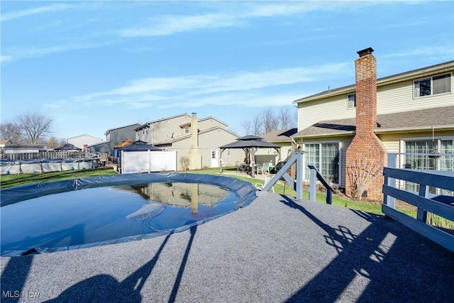 view of pool with a patio, fence, a gazebo, a residential view, and a fenced in pool